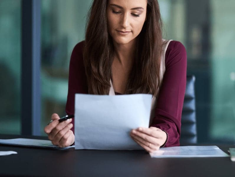 Woman forward facing sitting at desk reviewing paper document