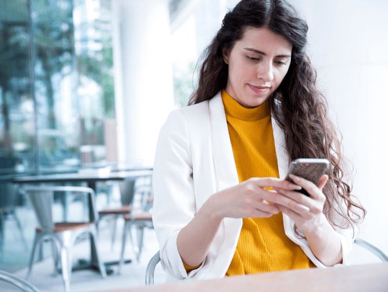 Female sitting a desk in an open area looking at her phone