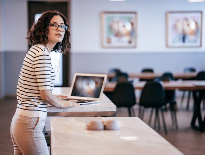 Woman standing in work environment a laptop looking of to her side