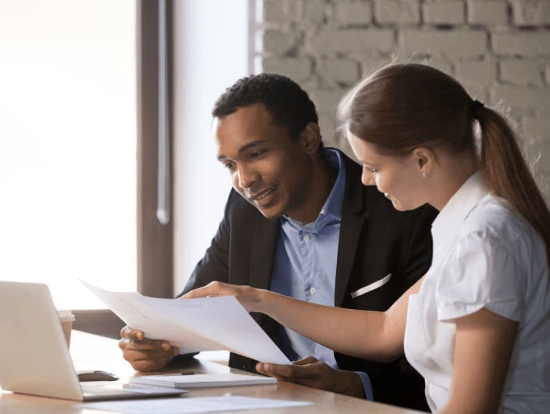 Female colleague is refreshing a paper as she shares details with her male colleage